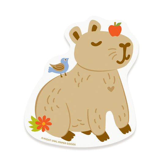 Vinyl sticker of a content capybara with an apple on its head, a bird on its back and a flower nearby.