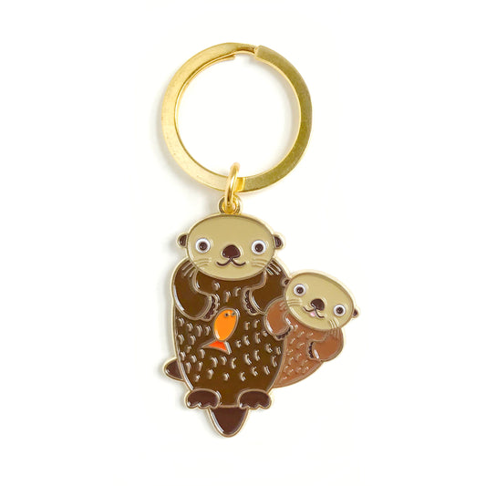 Gold metal otter enamel keychain featuring two playful brown otters and a small orange fish on a gold key ring