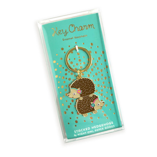 Stacked Hedgehogs enamel keychain on gold foil stamped backer card packaged in a clear gift box. Backer card reads "Key Charm Enamel Keychain" at top and "Stacked Hedgehogs by Night Owl Paper Goods" at bottom.