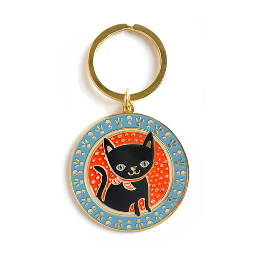 Gold metal black cat enamel keychain featuring a black cat with blue eyes on a round blue and orange patterned background on a gold key ring