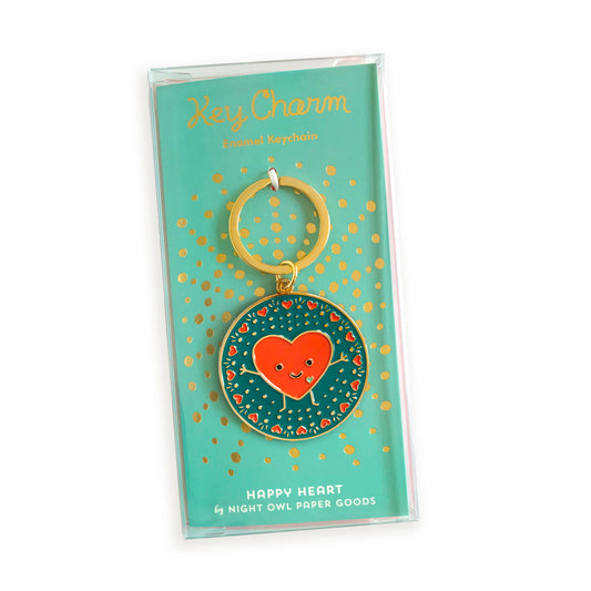 Happy Heart enamel keychain on gold foil stamped backer card packaged in a clear gift box. Backer card reads "Key Charm Enamel Keychain" at top and "Happy Heart by Night Owl Paper Goods" at bottom.