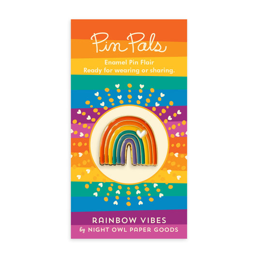 Rainbow enamel pin with a white heart and gold accents mounted on a rainbow striped backer card that reads "Pin Pals Enamel Pin Flair - Ready for wearing or sharing. RAINBOW VIBES by Night Owl Paper Goods."