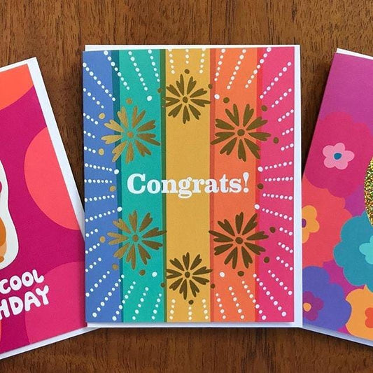 Colorful pastel striped greeting card with gold foil floral designs and 'Congrats!' text.