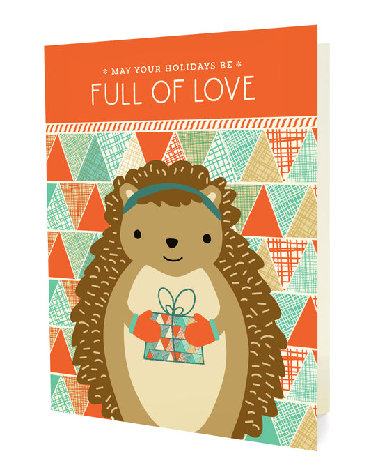 Front of a folded holiday card with a cute, gift-bearing hedgehog on a geometric patterned background with "May your holidays be full of love" text.