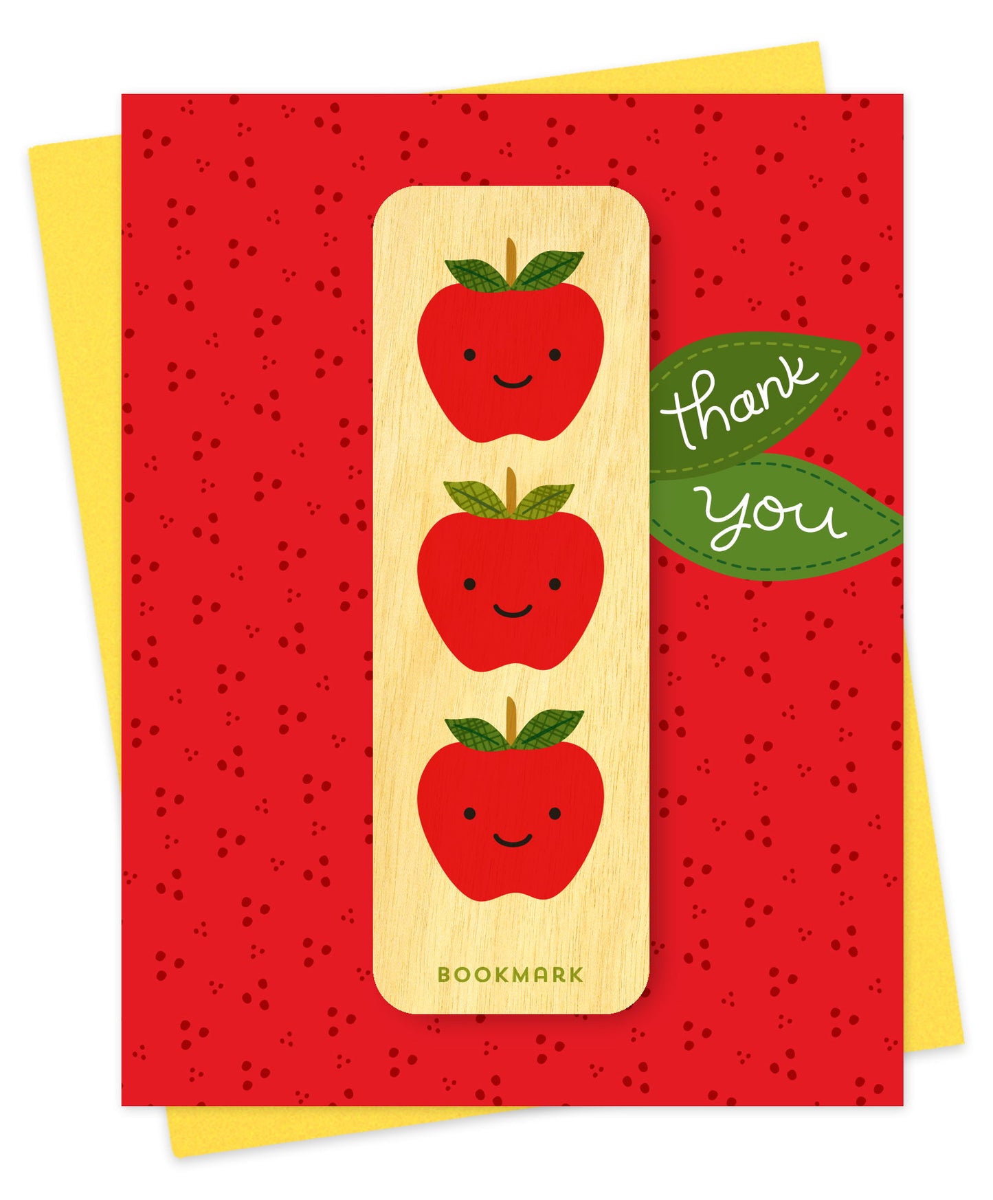 Folded thank you card with a bold red speckled background, thank you text on green leaves and a removable birch wood bookmark featuring three smiling apples. Pictured with a yellow envelope.