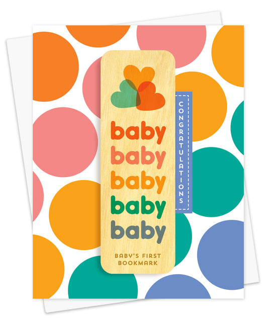 Folded new baby card with a white background, bold multicolor polka dot pattern and Congratulations text. It includes a removable birch wood bookmark with repeating "baby" text in various colors, a trio of overlapping hearts and "Baby's First Bookmark" label. Pictured with a white envelope.