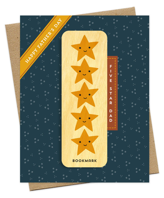 Folded Father's Day card with a deep blue background and scattered dot pattern, with a Happy Father's Day banner accent and Five Star Dad text. It includes a removable birch wood bookmark featuring five smiling gold stars. Pictured with a kraft envelope.