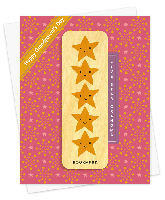 Folded Grandparent's Day card with a rosy pink background scattered with stars and confetti triangles, a Happy Grandparent's Day banner accent and Five Star Grandma text. It includes a removable birch wood bookmark featuring five smiling gold stars. Pictured with a white envelope.