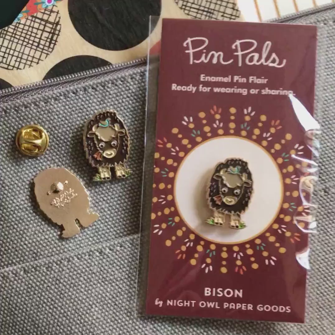 Front of enamel pin is a bison with gold accents. Back of pin is gold with the Night Owl Paper Goods script logo. Pin is mounted on a backer card that says "Pin Pals - Enamel Pin Flair - Ready for wearing or sharing - BISON - by Night Owl Paper Goods" and is packaged in a clear bag.