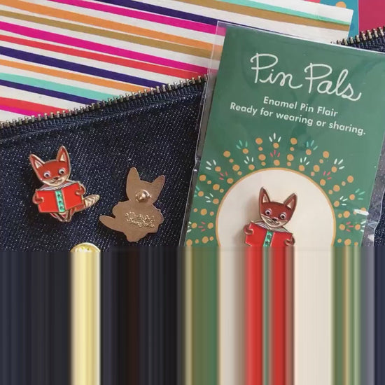 Front of enamel pin is a fox reading a book with gold accents and a small white heart. Back of pin is gold with the Night Owl Paper Goods script logo. Pin is mounted on a backer card that says "Pin Pals - Enamel Pin Flair - Ready for wearing or sharing - READING FOX - by Night Owl Paper Goods" and is packaged in a clear bag.