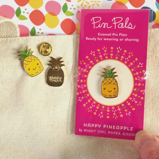 Front of enamel pin is a smiling pineapple with gold accents. Back of pin is gold with the Night Owl Paper Goods script logo. Pin is mounted on a backer card that says "Pin Pals - Enamel Pin Flair - Ready for wearing or sharing - HAPPY PINEAPPLE - by Night Owl Paper Goods" and is packaged in a clear bag.