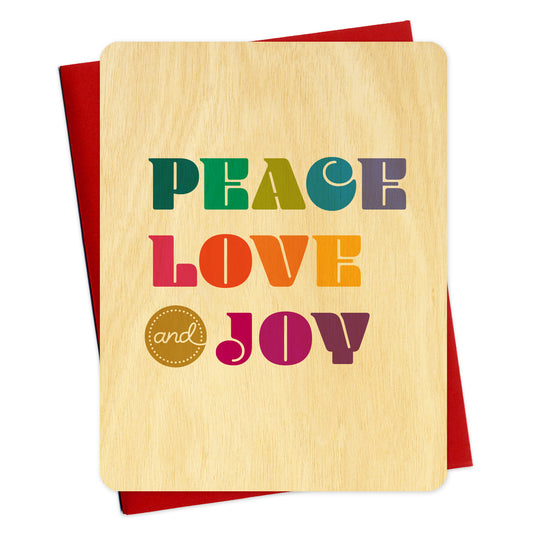 Flat birch wood holiday card featuring colorful, bold “PEACE LOVE & JOY” lettering in shades of green, teal, purple, pink, red and orange. Shown with a red envelope.