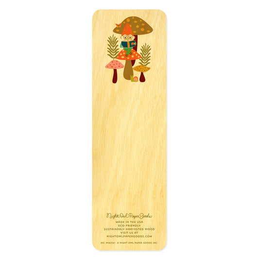 Back side of wooden bookmark with an illustration of a gnome sitting on a mushroom reading 