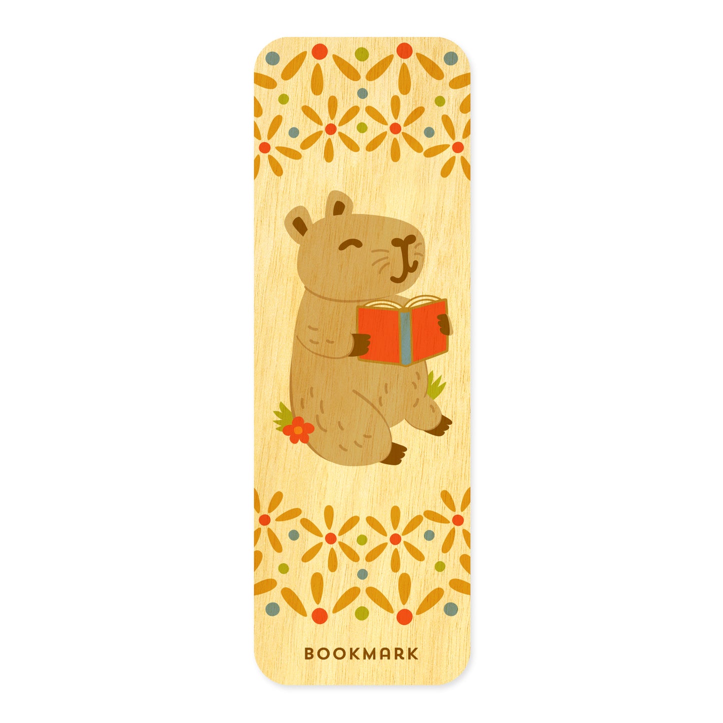 Front of Capy birch wood mini bookmark featuring a cute capybara holding an open red book, surrounded by decorative floral patterns in orange, yellow, green and blue at the top and bottom.